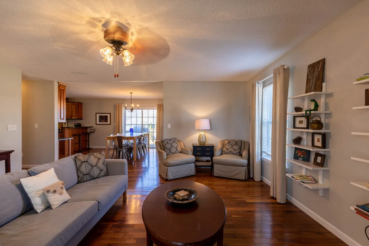 A spacious living area featuring a comfortable sofa, coffee table, lamp, and bookshelf, with a view into the dining area beyond. The space exudes a cozy and welcoming atmosphere, ideal for gathering after outdoor adventures.