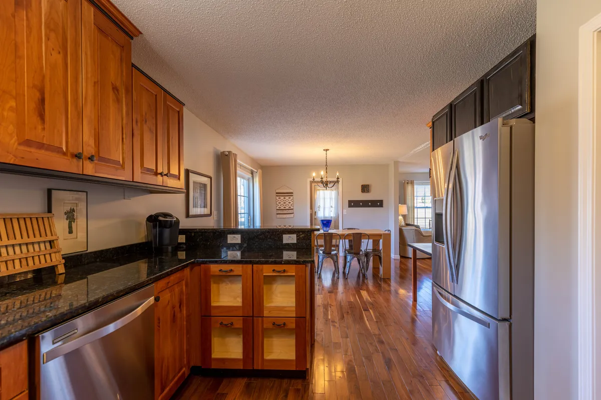 A warmly lit open-plan kitchen and dining area featuring sleek stainless steel appliances, inviting cabinetry, and a dining table that encourages gathering. The view subtly hints at a welcoming atmosphere where guests (and pets) can feel at home after a day outdoors.