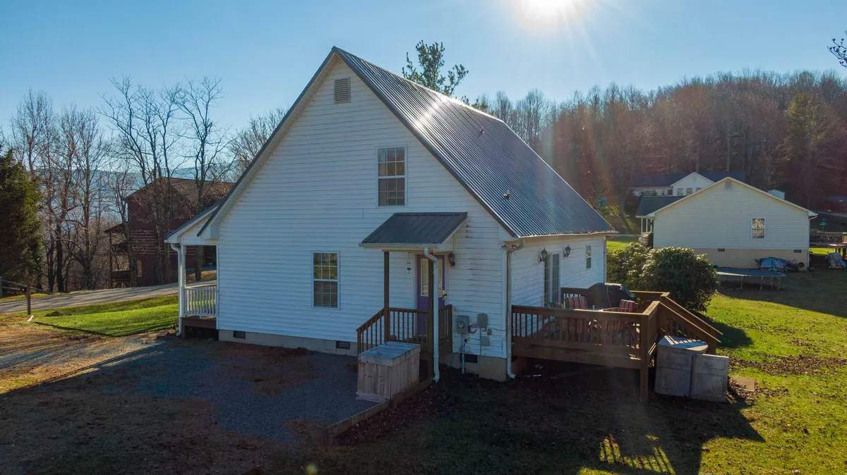 An exterior view of the home's structure with a well-maintained deck area and landscaped lawn, creating an inviting first impression. The scene is tidy, organized, and gives a sense of secure, cared-for entry.