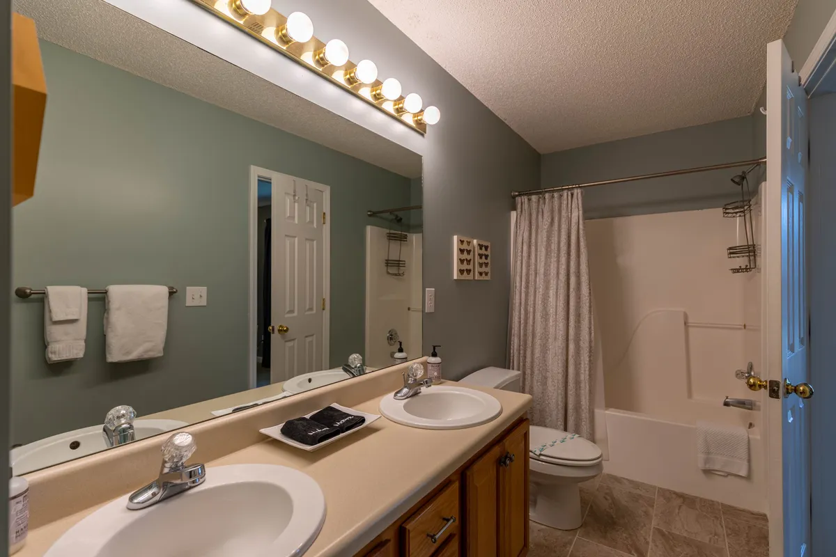 A modern, inviting bathroom with double sinks, a large mirror, and elegant lighting. The clean design evokes a spa-like ambiance, perfect for morning routines or evening relaxation.