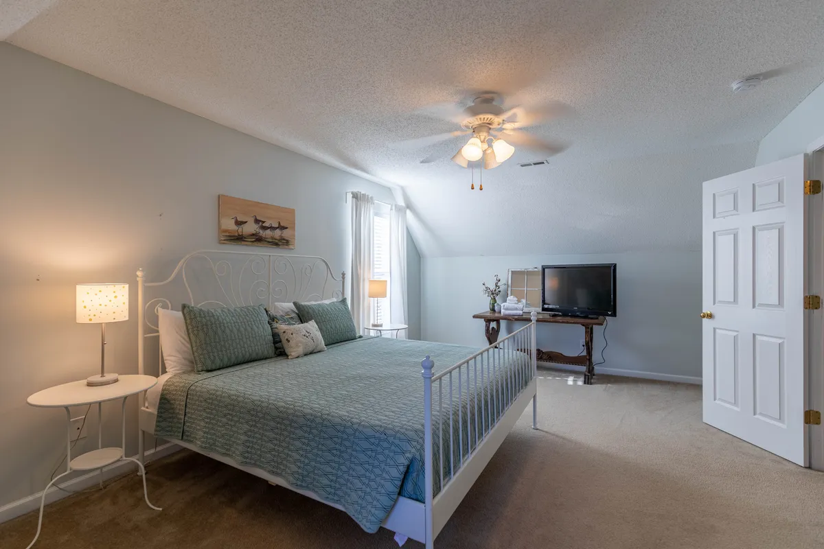 A tranquil bedroom with decorative bedding, a cozy nightstand with lamp, and calming wall art, all exuding a restful atmosphere. The space suggests a peaceful retreat where both people and pets can unwind and recharge.